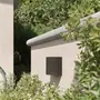 Moderne udendørs væglampe i sort, riflet metal, rektangulær form, monteret på lys mur, ideel til have eller terrassebelysning.