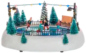 Miniatyr vinterscen med fyra skridskoåkare på liten isbana, omgiven av snötäckta träd, bänk, svart staket och färgglada ljusslingor. Dekorativ julprydnad med detaljerade figurer.