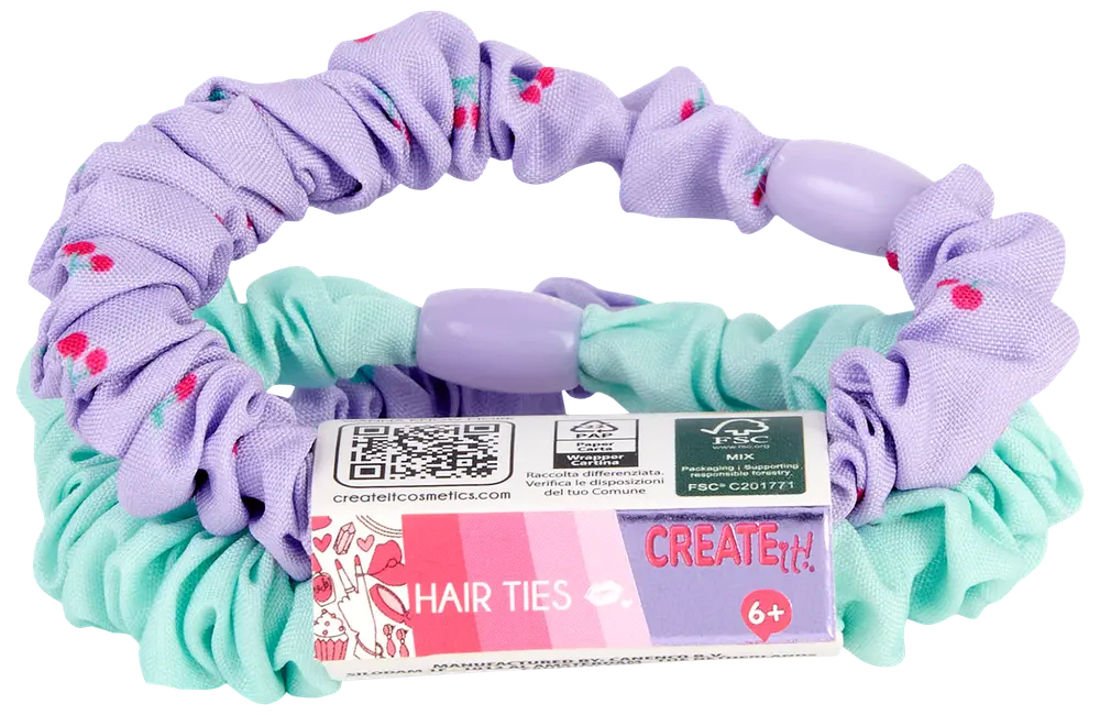 Sæt med to stofhårelastikker: én mintgrøn, én lilla med lyserøde prikker, begge med plastikperler. Velegnet til børn fra 6 år. Leveres med farverig etiket.