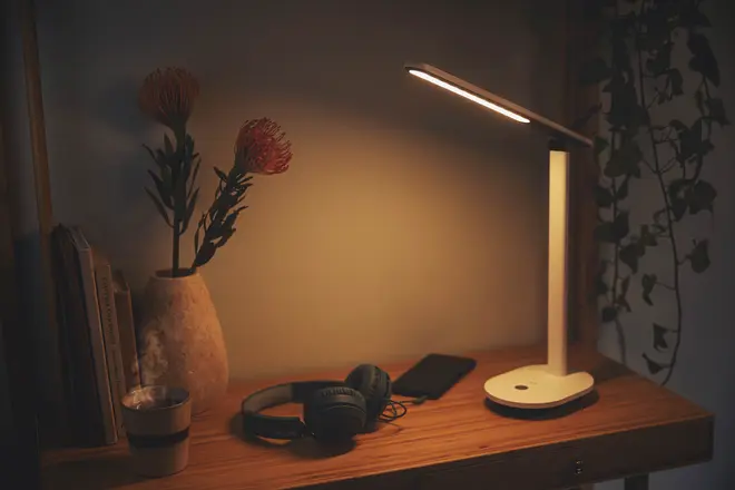 Moderne hvid LED-skrivebordslampe med slankt, justerbart arm og touch-kontrol på basen. Giver varmt lys, minimalistisk design, kompakt størrelse, ideel til skriveborde.