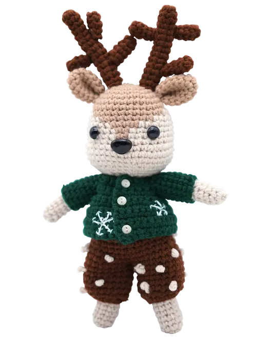 Handgjord virkad renmjukisdjur med bruna horn, grön tröja med vita snöflingor och bruna shorts med vita prickar. Mjuk och perfekt som juldekoration eller present.