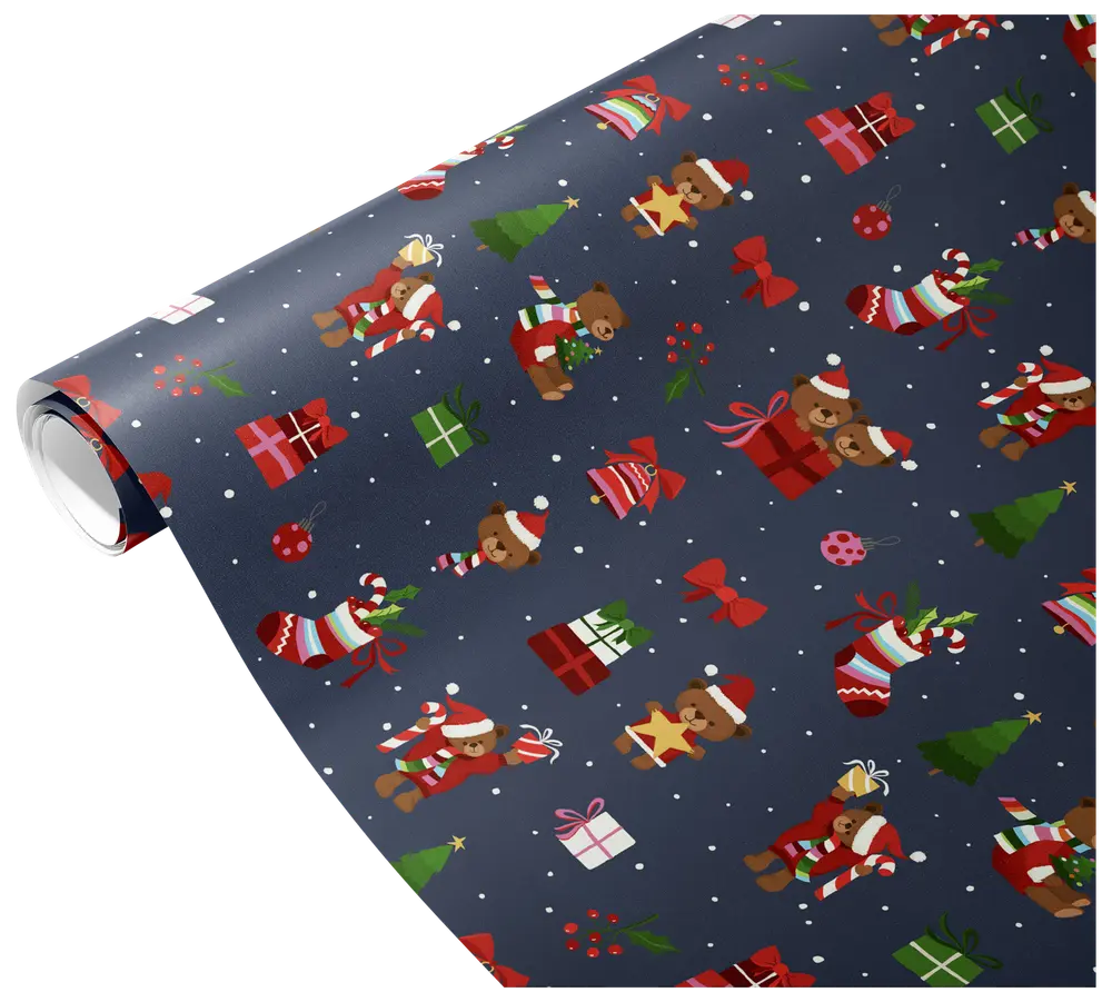 The image shows a roll of wrapping paper with a festive Christmas design. The background is dark blue and features a repeating pattern of teddy bears wearing Santa hats and scarves, Christmas trees, wrapped gifts in various colors, red bows, stockings filled with presents, holly sprigs, and snowflakes. The overall look is playful and colorful, suitable for holiday gift wrapping.