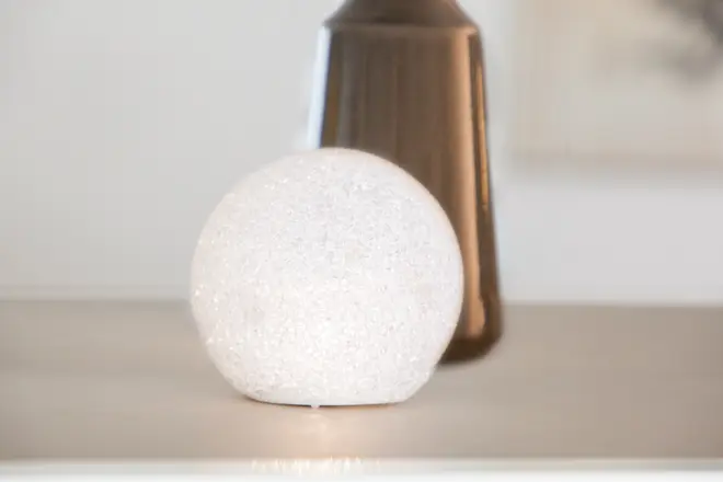 Rund vit LED-bordslampa med textur, ger mjukt omgivande ljus. Modern design, kompakt storlek, energisnål, dekorativ detalj för vardagsrum eller sovrum.