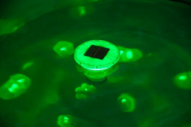 Solcellsdriven flytande LED-poollampa, rund design, avger grönt ljus, vattentät, passar pool eller damm, solpanel på ovansidan, tänds automatiskt på natten.