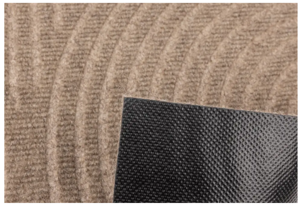 Närbild av beige matta med böjda linjer och svart halkfri gummibaksida för säker placering på golv.