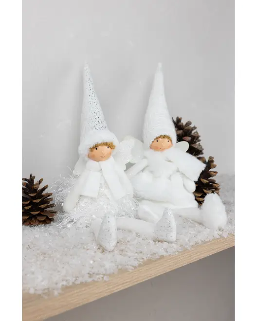 Två vita julälvsfigurer med spetsiga hattar, halsdukar och glittriga detaljer sitter bland konstsnö och kottar. Perfekt för juldekoration på hyllor eller spiselkrans.