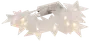 Lyskæde med stjerneformede LED-lys og hvide, gennemsigtige plastikskærme. Udsender et varmt hvidt skær, velegnet til indendørs dekoration. Batteriboks medfølger.