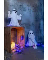 Set med två keramiska spökfigurer, en med solglasögon, LED-ljusslinga med lila spindlar, batteriljus och trälåda. Perfekt för Halloween-dekoration inomhus.