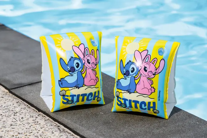 Et par oppustelige gule svømmevinger med Disney’s Stitch og Angel figurer, sol- og strandmotiv samt teksten “STITCH” nederst på vingerne.