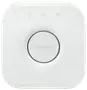 Hvid Philips Hue Bridge smart home-hub, firkantet med afrundede hjørner, central rund knap, diskret logo og tre små indikatorikoner øverst.