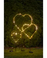 Set med tre hjärtformade LED-trädgårdslampor på pinnar, med varmvita lampor i olika storlekar, perfekta för dekorativ belysning i trädgård eller längs gångväg.