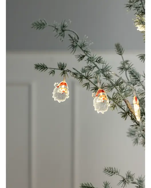 Sæt med små julemandsansigtsornamenter med røde huer og hvide skæg, hængende på en juletræsgren. Perfekt til juleudsmykning.