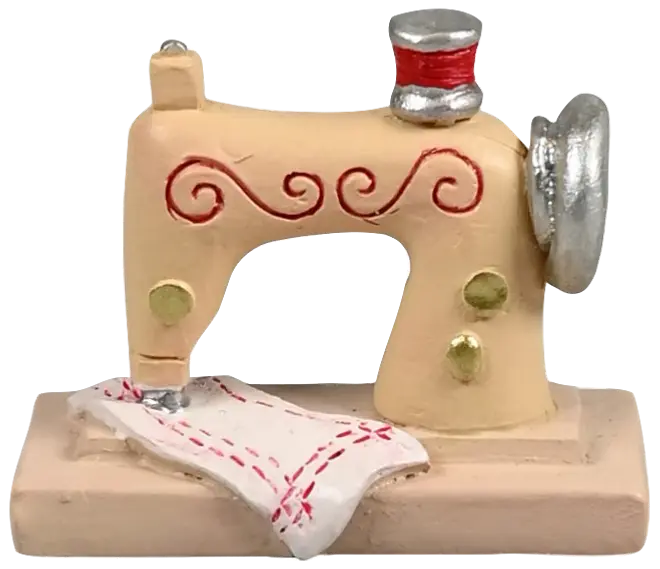 Miniature symaskinefigur, beige med røde og gyldne detaljer, sølvfarvede elementer og et hvidt stofstykke med røde sting, monteret på rektangulær base. Dekorativ samlergenstand.