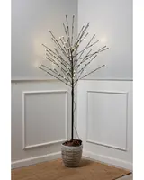 Tall decorative tree with slender black branches, each tipped with small warm white LED lights. The tree is placed in a textured, light gray pot filled with pinecones. The design is minimalist and modern, suitable for indoor use as accent lighting or seasonal decoration.