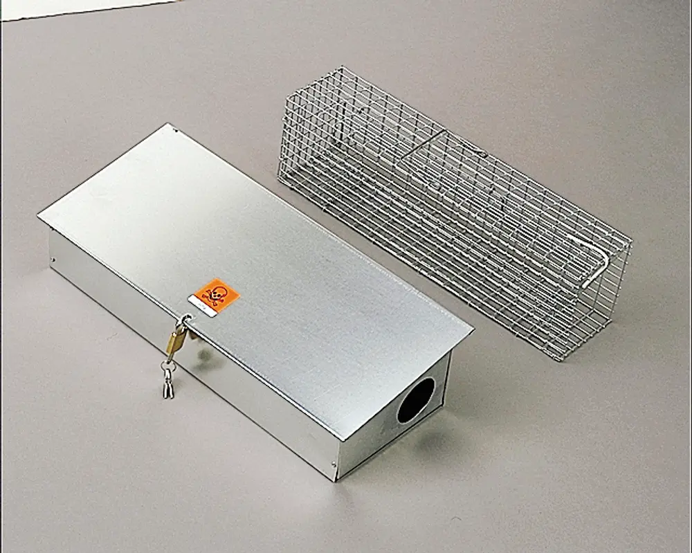 Metalfælde til dyr med aflåselig boks og trådbur. Boksen har biohazard-mærkat, nøglelås og rundt indgangshul i den ene ende.