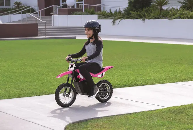 Børns elektriske crossmotorcykel i pink med sorte og hvide detaljer, nummer 2 foran og på siderne, grove dæk og solid ramme. Egnet til udendørs brug, inklusiv sikkerhedshjelm.