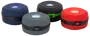 Sæt med fire kompakte, runde LED campinglanterner i blå, sort, grå og rød. Hver har centralt lys, sort bånd med knap og robust plastkonstruktion.