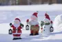 Tre festlige julefigurer til udendørs brug: julemand med lanterne, julemand med skiltet 'Glædelig jul' og snemand med grøn tørklæde.