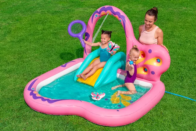 Oppustelig børnepool i pink med sommerfugletema, lille rutsjebane, bue og vandsprøjte. Inkluderer legetilbehør. Velegnet til små børn, til udendørs brug på græs.