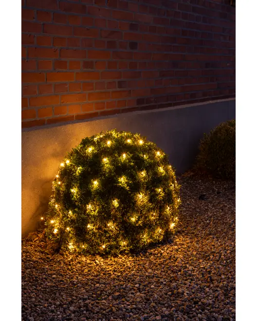 Udendørs busk dækket med varm hvide LED-lyskæder, der skaber en glødende dekorativ effekt. Perfekt til have eller terrasse. Lysene er jævnt fordelt for festlig stemning.