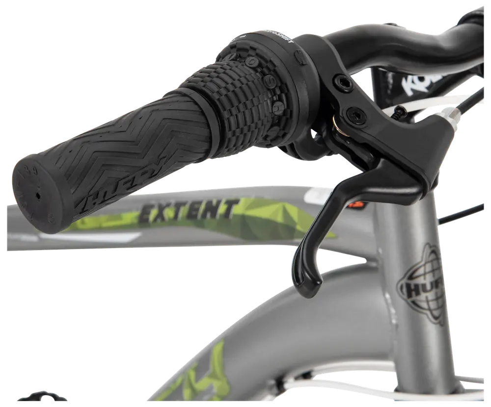 Närbild av cykelstyre med texturerat gummihandtag, vridreglage och bromshandtag. Silverfärgad ram med gröna detaljer och texten 'EXTENT' synlig.