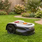 Robotplæneklipper med sort og hvidt design, store robuste hjul og kontrolknapper på toppen. Ideel til automatisk græsslåning i haver, egnet til mellemstore plæner.