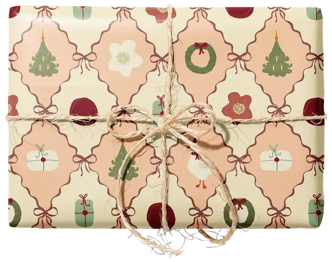 Inslagen presentlåda med cremefärgat julpapper med träd, kransar, blommor och paket, bunden med rustikt snöre och rosett.