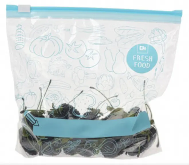 Gennemsigtig genlukkelig plastpose med blå lynlås, mærket 'Fresh Food', indeholder mørke kirsebær med stilke. Dekorative madillustrationer på posen. Velegnet til opbevaring af friske varer.