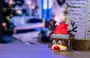 Lille rensdyrfigur med rød julemandskasket, brune gevirer og store øjne. Figuren er oplyst indefra og står ved siden af et hvidt kunstigt juletræ på træoverflade.