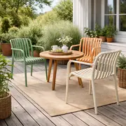 Stabelstole i henholdsvis grøn, orange og sandfarvet omkring et træbord på træterrasse