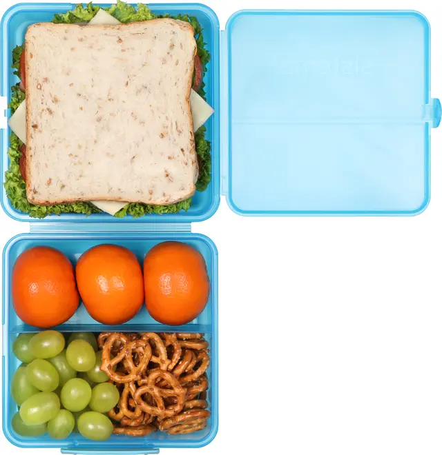 Blå plastik madkasse med tre rum, indeholder en sandwich, tre mandariner, grønne druer og små saltkringler. Madkassen har hængslet låg og organiserer måltidet.