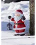 Festiv julemandfigur i rødt outfit med sort lanterne, til udendørs juledekoration, stående i sne ved et træ.
