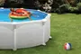 Rund fritstående pool med hvid yderside, fyldt med vand. Inkluderer en farverig badering. Poolen står på grøn græsplæne med en strandbold i nærheden.