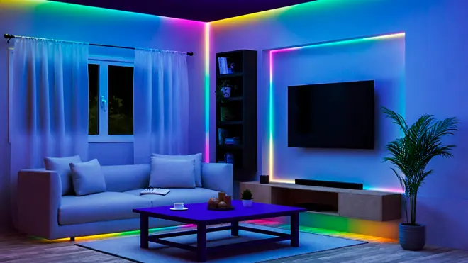 Moderne stue med flerfarvede LED-lysbånd langs loft, TV-væg og under møbler. Grå sofa, blåt sofabord og en potteplante er inkluderet.