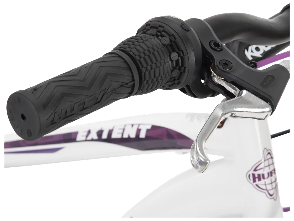 Närbild av cykelstyre med svart, mönstrat gummihandtag, vridväxel och silverfärgad bromshandtag, monterat på vit ram med lila och svarta detaljer.