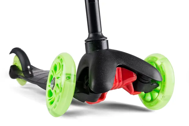 Nærbillede af løbehjul til børn med tre neongrønne hjul, sort stel og røde detaljer. Foran er der to hjul for ekstra stabilitet og et bredt dæk.