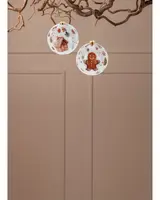 Set med två julgranskulor i glas, en med pepparkaksgubbe och en med pepparkakshus, båda dekorerade med festliga motiv och guldfärgade snören.