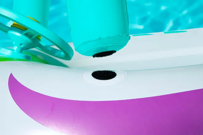 Nærbillede af en oppustelig badering med aftagelig del fastgjort med velcro, lilla og hvid krop samt turkis rat, beregnet til brug i vand.