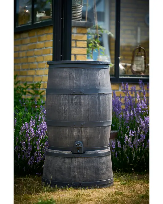 Stor, mørkegrå regnvandstønde med træstruktur, metalbånd og tappehane nederst til udendørs brug i haven. Tøndeformet design.