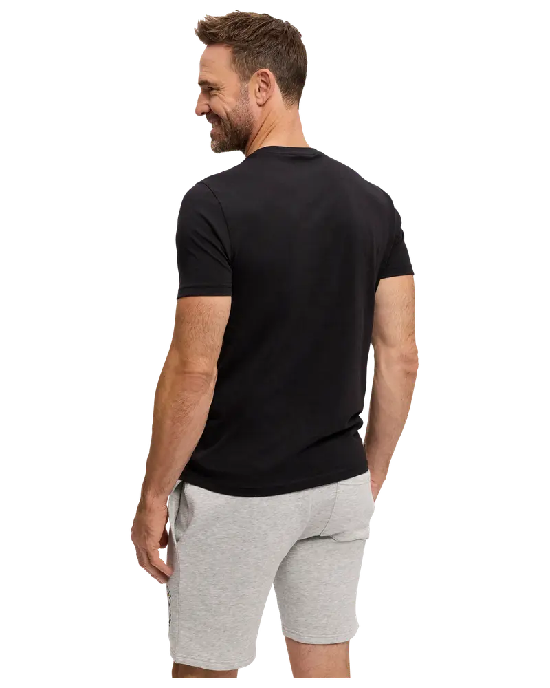 Man med enkel svart t-shirt med kort ärm och ljusgrå shorts med dragsko och sidofickor. T-shirten har normal passform och inga synliga tryck.