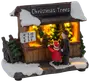Miniatyr julgransstånd med snö, belyst insida, prisskylt och två figurer (vuxen och barn) som handlar. Detaljerad och festlig dekoration.