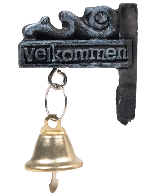 Vægmonteret metalskilt med teksten 'Velkommen' og dekorativt mønster, samt en hængende messingklokke fastgjort med metalringe. Velegnet til indgang eller dør.