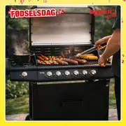 Stor sort gasgrill med seks drejeknapper, sidebrænder med gryde, åben låg, grillpølser, spyd og majs. Rustfri grillområde, udendørs brug, robust design.
