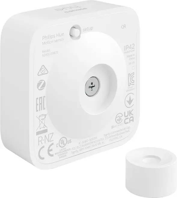 Hvid Philips Hue bevægelsessensor, firkantet med afrundede hjørner, centralt sensorøje, setup-knap og medfølgende monteringsdel. Kompakt design til smart home-automatisering.