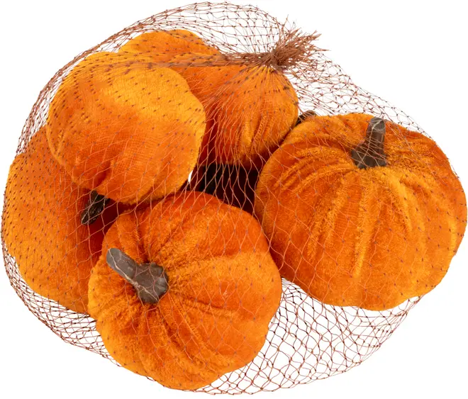Set med fem konstgjorda orange pumpor med bruna stjälkar, tillverkade av mjukt sammetstyg, förpackade i en brun nätpåse. Perfekt för höstdekoration.