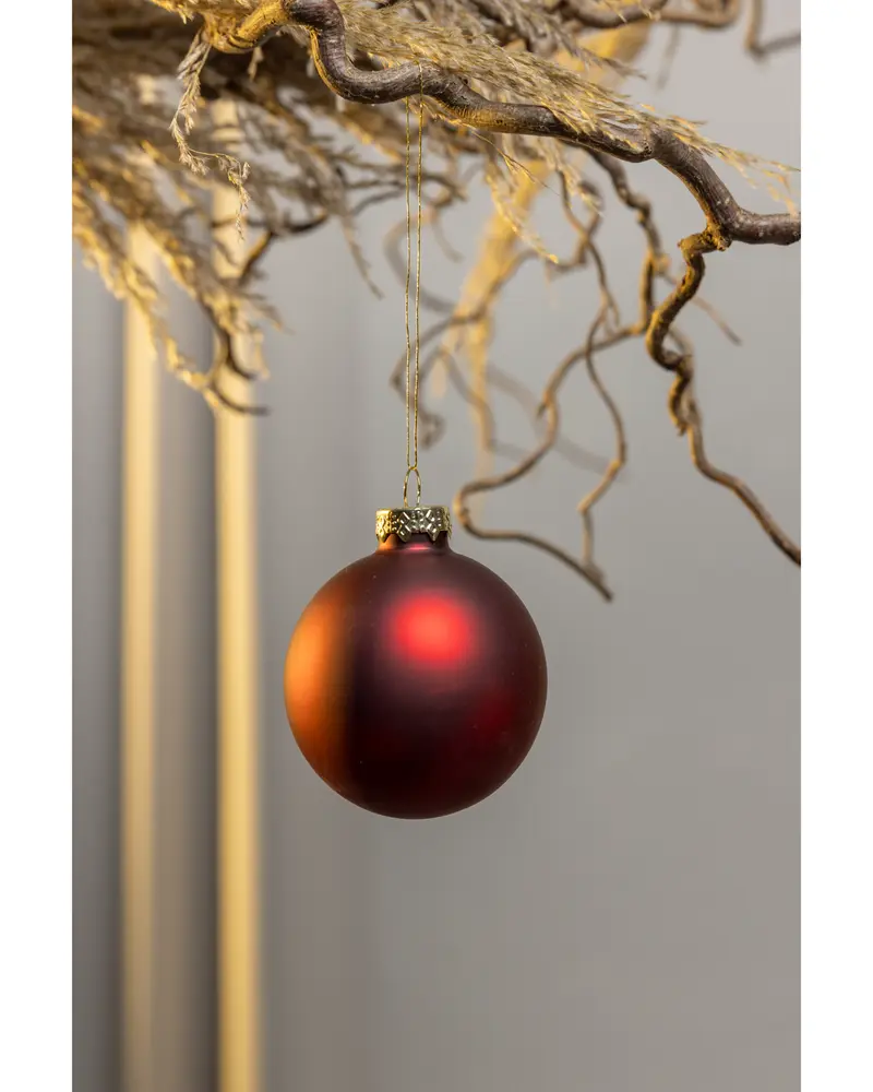 Matt röd julgranskula med guldfärgad topp, hängande i tunn guldsnöre. Enkel och klassisk dekoration för julgran eller hemmet.