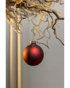 Matt röd julgranskula med guldfärgad topp, hängande i tunn guldsnöre. Enkel och klassisk dekoration för julgran eller hemmet.