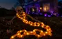 Halloween-dekoration med et skelet og en lysende orange lyskæde, velegnet til udendørs brug. Kæden lyser op og skaber en uhyggelig stemning til haven.