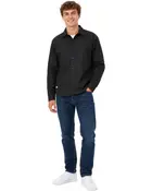 Herroutfit med svart skjorta med knappar och bröstfickor, mörkblå jeans och vita sneakers. Skjortan har klassisk krage och långa ärmar.