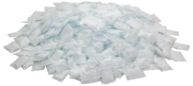 En stor hög med individuellt förpackade tvättmedelskapslar, varje kapsel är vit och rektangulär, förseglad i klar plast för engångsbruk.